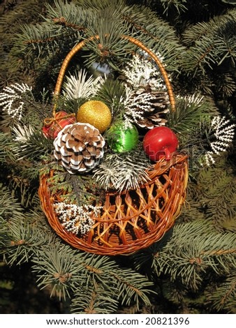 Christmas decoration - christmas basket with balls and strobiles on branch of fir tree.