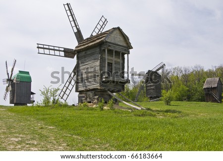 Wooden windmills on green field, recorded in outdoors museum of national architecture in Pirogovo, near Kiev, capital of Ukraine.