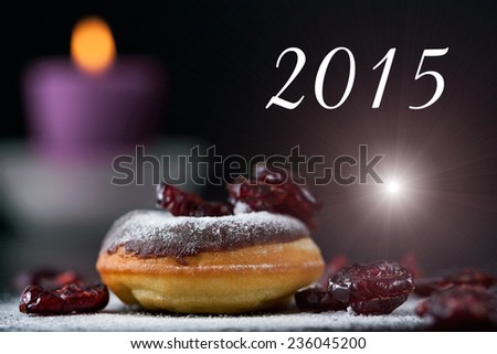 Delicious donut topped with chocolate and cranberries. Romantic atmosphere with text message, candle in background. Shallow depth of field.