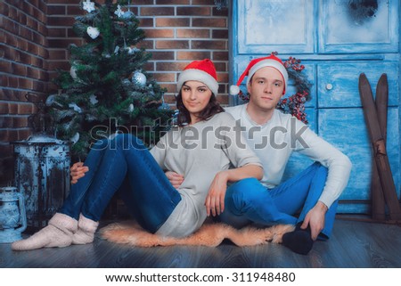 Holidays, New year and Christmas. Couple man and woman sitting on the floor of the house near the Christmas tree and hug.