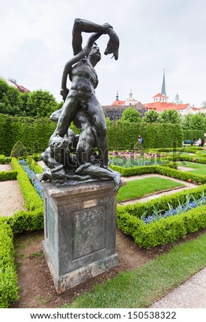 PRAGUE, CZECH REPUBLIC - MAY 8, 2013: One of the bronze sculptures in Wallenstein Gardens (Valdstejnska zahrada). In the background is the palace Wallenstein; May 8, 2013 in Prague, Czech Republic.
