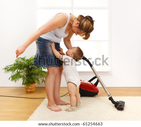 Mother cleaning the floor while she\'s baby is crying and wants to be picked up