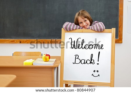 School girl in classroom, behind a board with Welcome Back script