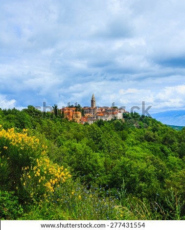 Small village with ancient buildings and church on top of hill surrounded by  flowers and trees in spring time at Labin, Croatia.