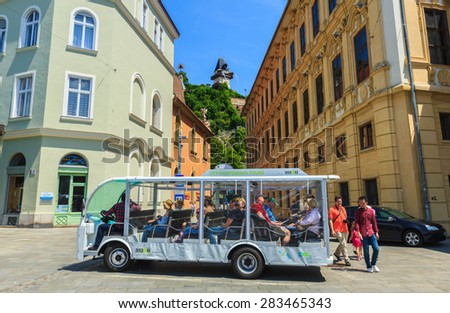 GRAZ, AUSTRIA- MAY 30: Tourist bus waiting for tourists for the city sight-seeing tour at the square with the view of clock tower on the hill on background in Graz, Austria on May 30, 2015.