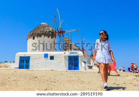 MYKONOS, GREECE- JUNE 16: Tourists enjoying the sight- seeing at the famous tourist spot of windmills on island Mykonos, Greece on June 16,2015. Windmills from the 16th century, landmarks of Mykonos.