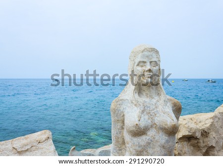PIRAN, SLOVENIA- MARCH 20: Portrait of beautiful mermaid statue on the rocky coastline of Piran, Slovenia on March 20, 2015. Mermaid sculpture carved out of the stone rocks that surround Peninsula.