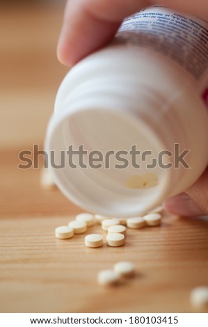 Pills spilling out of white pill bottle