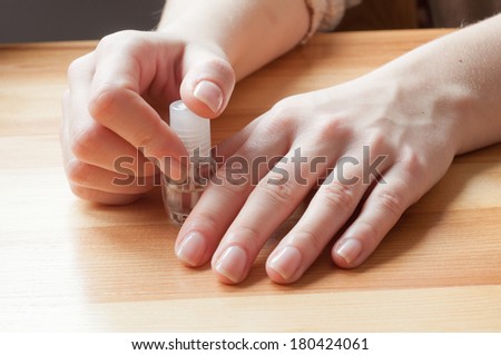 Twisting the bottle of  transparent nail polish