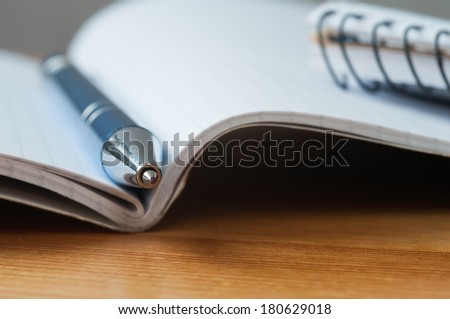 A metal pen between the pages of a exercise book. Macro image with shallow depth of focus.