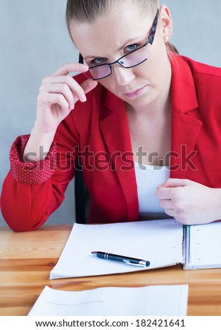 Young woman attentively observing from behind her glasses.