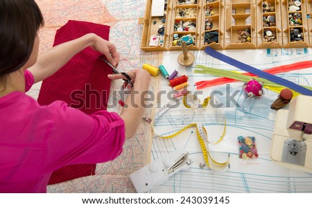 Woman sewing at home with sewing paper patterns.