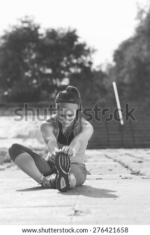 Woman doing  warm-up exercises before running.Photo is carefully post processed to mach old black and white  film look.Soft focus, shallow depth of field.