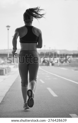 Woman running on the running track during a workout.Photo is carefully post processed to mach old black and white film look.