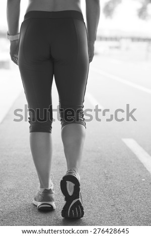 Legs of a woman running on the running track during a workout.Photo is carefully post processed to mach old black and white film look.