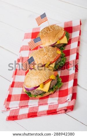 American beef burgers with cheese with USA flags on the white wooden table. Selective focus and small depth of field.