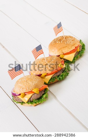 American beef burgers with cheese with USA flags on the white wooden table. Selective focus and small depth of field.
