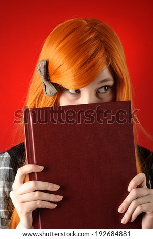 Beautiful young girl with red-orange hair with book