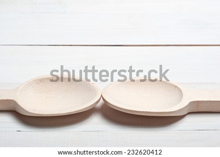 Two wooden spoons on white wooden table