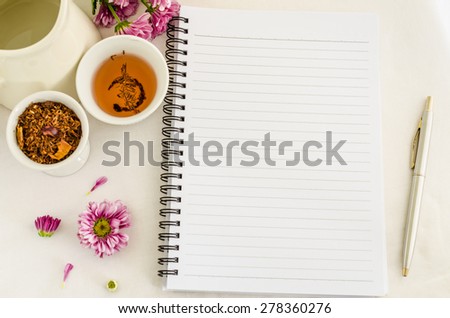 a blank notebook, pen,  purple Chrysanthemum flowers and roibos tea on white table