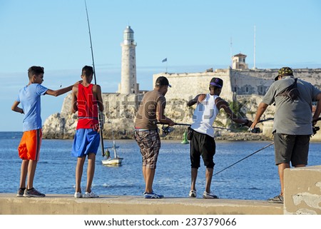 Havana, Cuba - October 30, 2014: Young men are fishing in the Malecon quay. Fishing is a common hobby in Cuba. It allows fishermen to get food and earn extra money