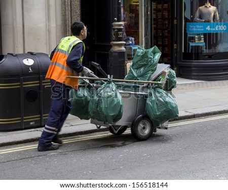 LONDON,UK - MAY 25, 2013: A street cleaner pushing his trolley full of waste bags on May 25 2013