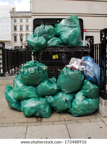 LONDON, UK - 28TH JULY 2013: A bin with overflowing green rubbish bags