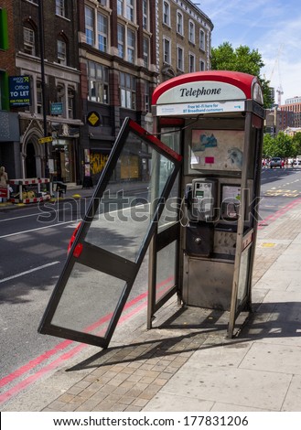LONDON, UK - 15TH JULY 2013: A damaged public telephone box in London with the door hanging off