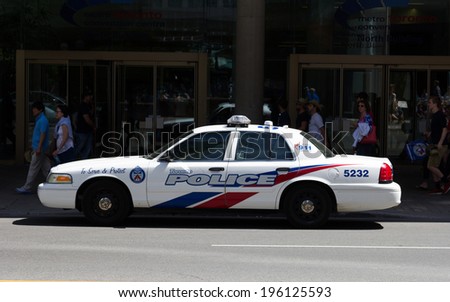 TORONTO, CANADA - JUNE 1, 2014: A Toronto Police car parked on a street with people walking past in the background