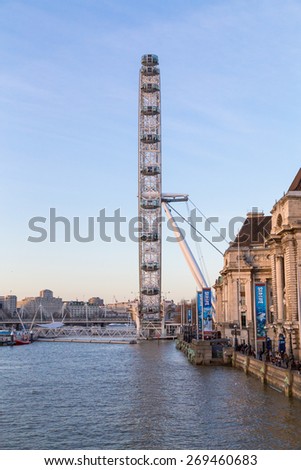 LONDON, UK - 10TH MARCH 2015:  The London Eye from the side. Part of County Hall and The Queens Walk can be seen.