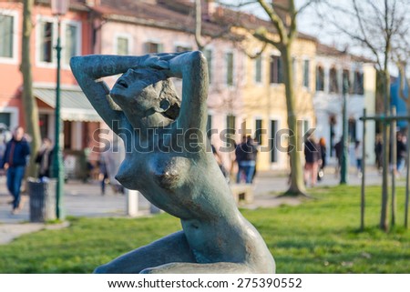 BURANO, ITALY - 14TH MARCH 2015: La Tua Pace statue near Burano port. Large amounts of people can be seen in the distant