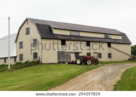 CAPE BRETON, CANADA - 5TH JULY 2015: The outside of a Barn with a red tractor outside it during an overcast day in the summer