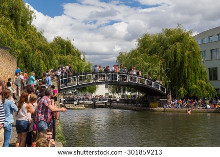 LONDON, UK - 19TH JULY 2015: A bridge in Camden Lock with lots of people on the bridge and at the side of the water. A man can be seen climbing out of the water.