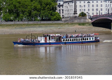 LONDON, UK - 18TH JULY 2015: A boat on the River Thames in London. Lots of people can be seen on the boat.