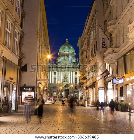 VIENNA, AUSTRIA - 27TH JULY 2015: A view along Kohlmarkt in Vienna at night showing the outside of buildings and the blur of people. Part of the Hofburg can be seen in the distance.
