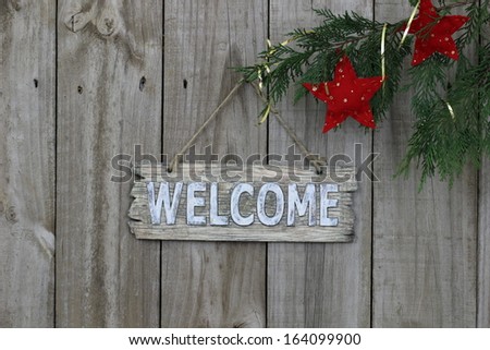 Wood welcome sign on fence with red stars hanging from tree