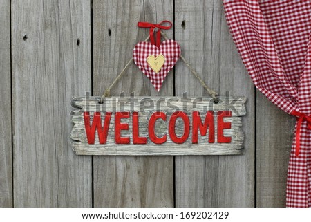 Red wood welcome sign with heart hanging next to gingham curtain