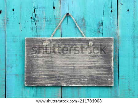 Blank rustic wood sign hanging on antique teal blue wooden background