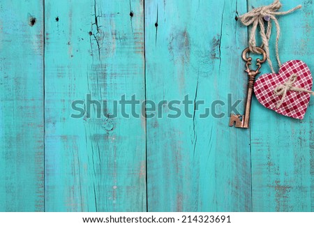 Bronze skeleton key and red checkered heart hanging on antique teal blue distressed wood door