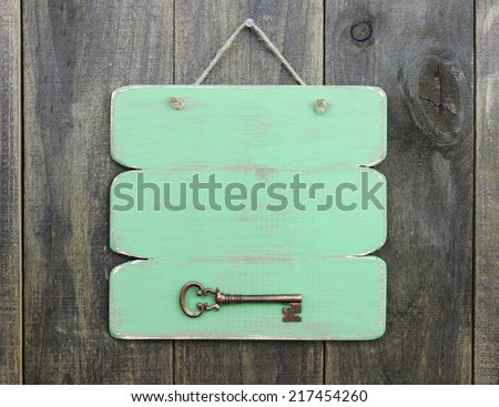 Blank wood green sign with bronze antique skeleton key hanging on rustic wooden door