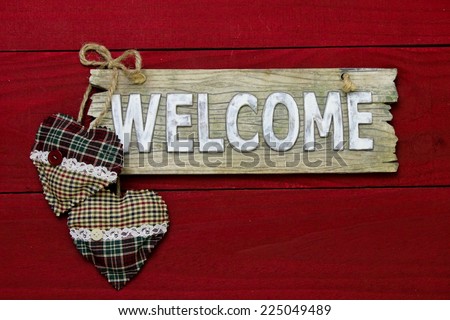 Rustic wood welcome sign with red and green plaid country hearts hanging on dark red barn door