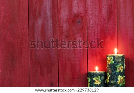 Textured autumn candles with leaves burning by antique red wooden background