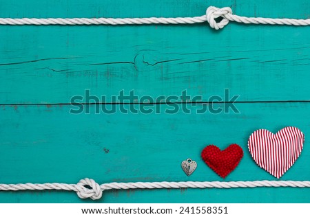 Red heart , candy cane striped heart and silver lock by white rope with knot border on blank antique teal blue weathered wooden background