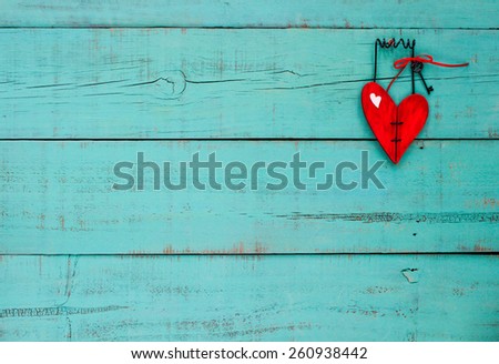 Country wood red heart with iron key and ribbon hanging on antique teal blue wooden background