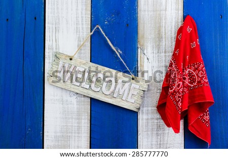 Welcome sign and red handkerchief or bandana hanging on blue and white rustic wood background