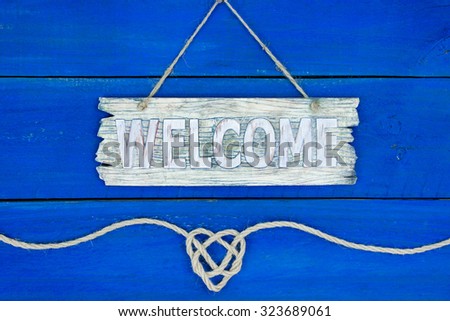 Welcome sign with rope heart border hanging on rustic antique blue wood background