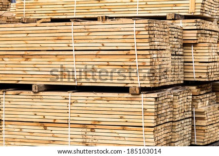 A pile of wood edged boards packed in stacks with tags size parameters for loading cranes and transport the cargo ships in the seaport