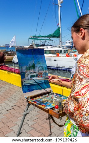 Artist draws a brush and oil paints bright seascape with yachts in the yacht club sea trading port of Odessa