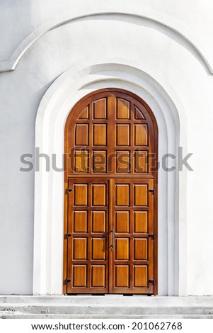 Modern Wooden door of a white stone wall entrance to the Christian church
