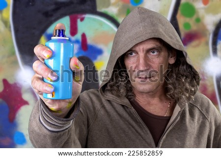 Graffiti artist in a gray dress with hood spray paint for picture on the wall of urban culture. Beautiful street art graffiti. Urban Contemporary Culture. Isolated on white background. selective Focus